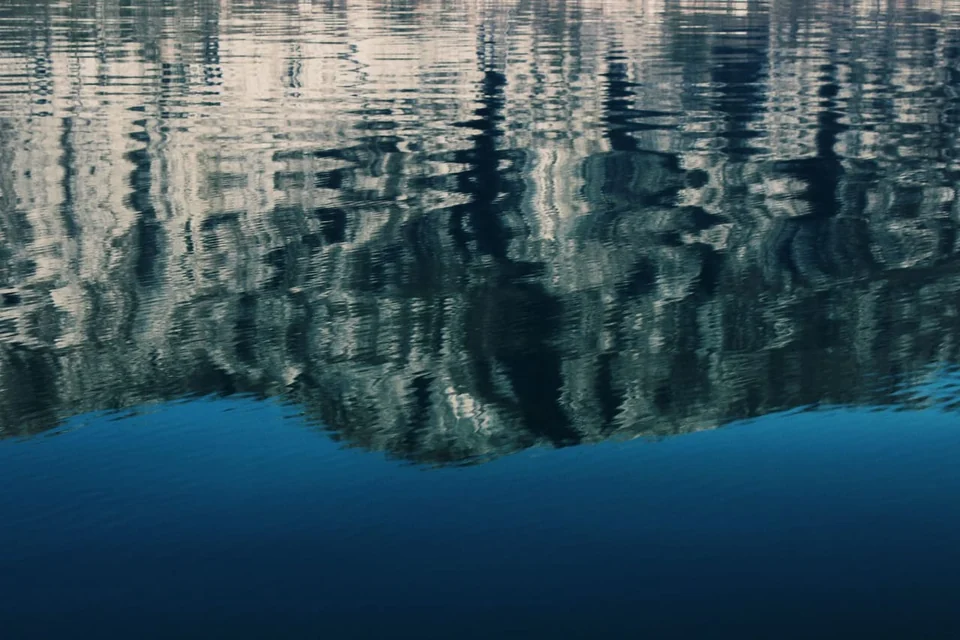 Mountain reflections forming rippled patterns on the water in Boka Bay.