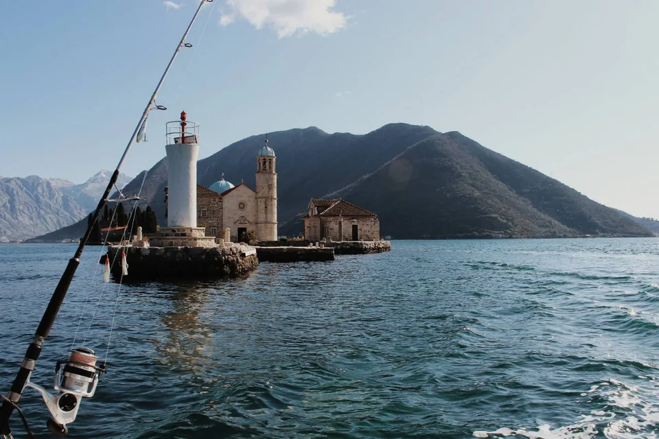 Our Lady of the Rocks in Boka Bay with mountains and a fishing rod in view.