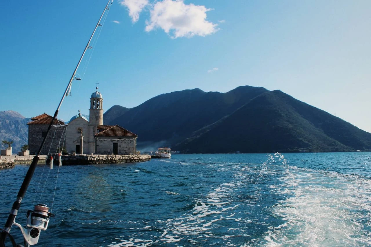 The boat's wake beside Our Lady of the Rocks, with Boka Bay mountains behind.