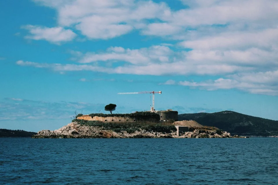 Stone fortifications on a low rocky island, seen across the water.