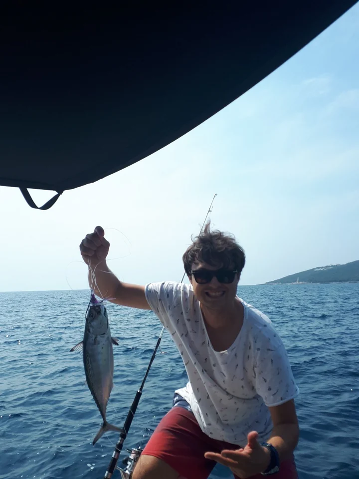 A guest holding up a caught fish aboard the boat.